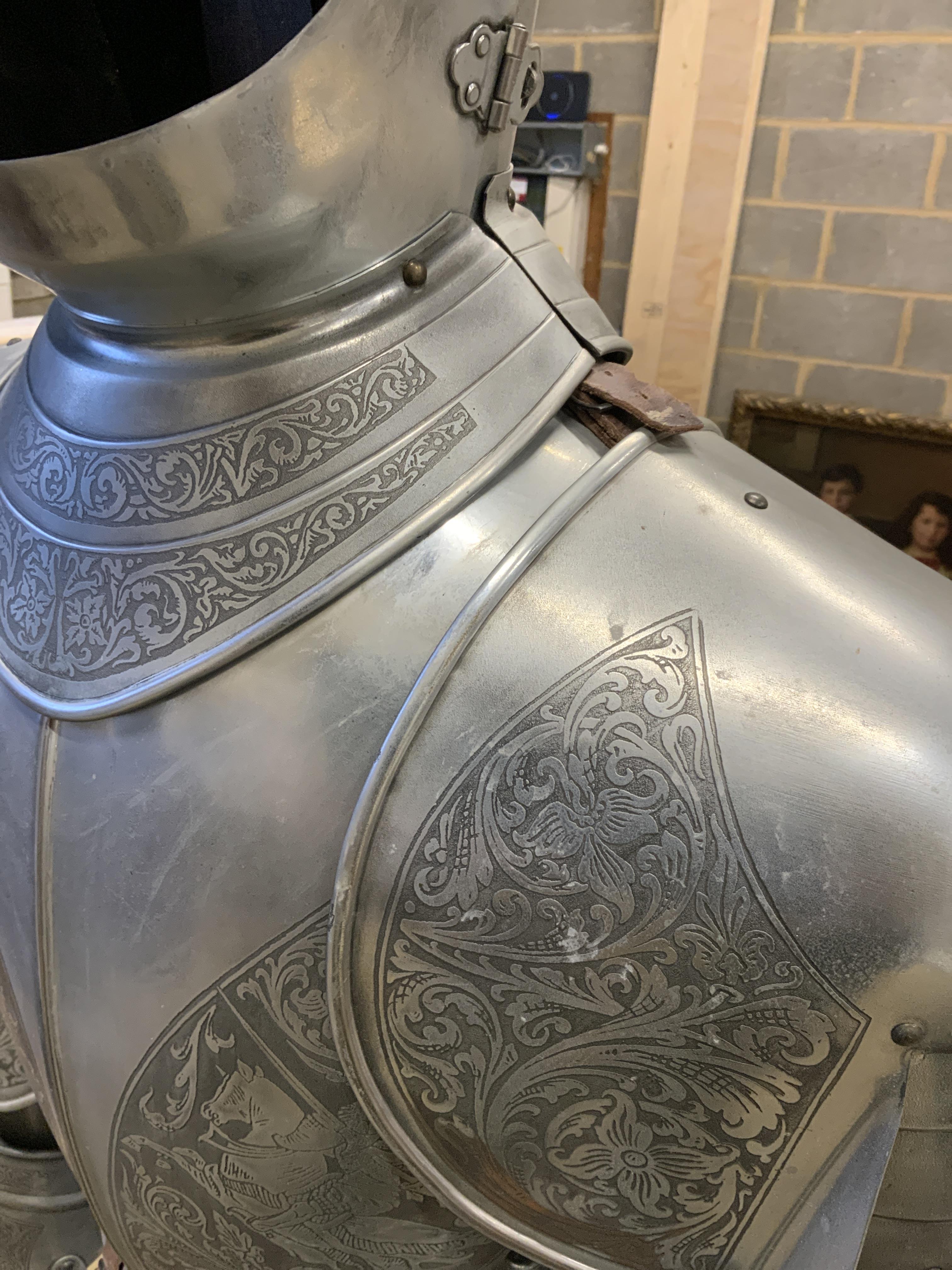 A full suit of reproduction armour produced in Spain by Marto, etch engraved decoration and including a broadsword, mounted on a display plinth and stand with applied makers label